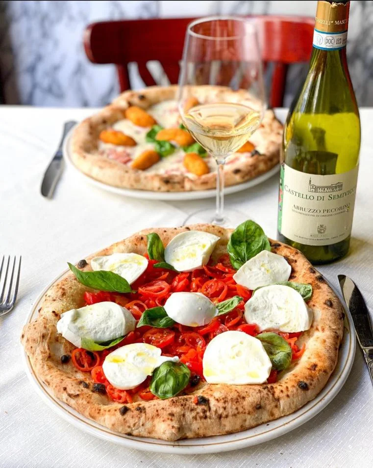 Foto von zwei Pizzen mit Wein